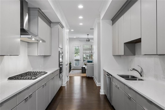 kitchen with sink, wall chimney range hood, gray cabinets, appliances with stainless steel finishes, and dark hardwood / wood-style flooring