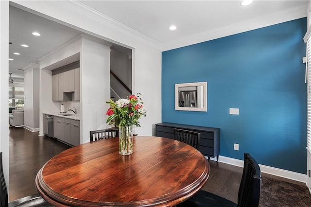 dining area featuring dark hardwood / wood-style flooring, crown molding, and sink