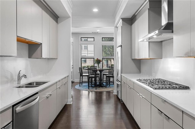 kitchen featuring dark wood-type flooring, sink, wall chimney exhaust hood, stainless steel appliances, and crown molding