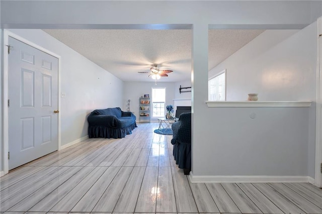 151 River Park Cir, Mcdonough, GA 30252 - living room with a ceiling fan, light wood-style floors, a fireplace, a textured ceiling, and baseboards