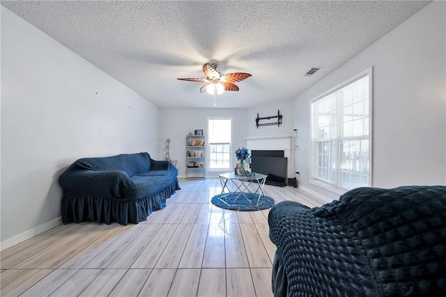 151 River Park Cir, Mcdonough, GA 30252 - living area with ceiling fan, a textured ceiling, a fireplace, baseboards, and light wood-type flooring
