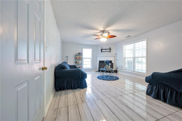 151 River Park Cir, Mcdonough, GA 30252 - bedroom with multiple windows, a textured ceiling, a fireplace with raised hearth, ceiling fan, and baseboards