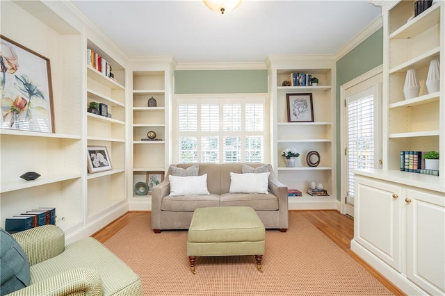 sitting room with light hardwood / wood-style floors, built in shelves, and ornamental molding