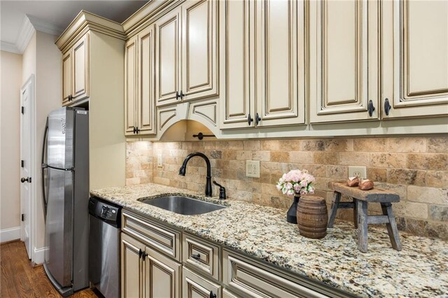 kitchen with sink, ornamental molding, appliances with stainless steel finishes, cream cabinetry, and wood-type flooring