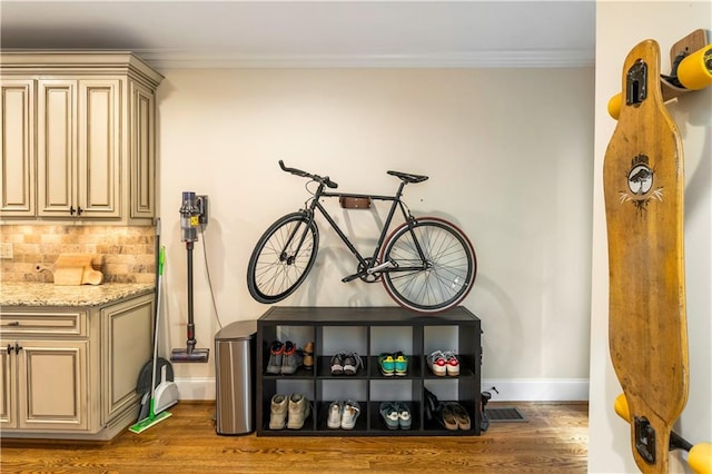 room details featuring hardwood / wood-style flooring, tasteful backsplash, and ornamental molding