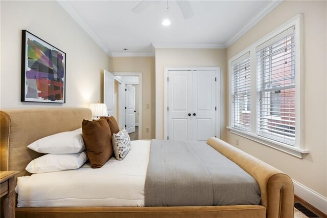 bedroom featuring ceiling fan, wood-type flooring, ornamental molding, and a closet