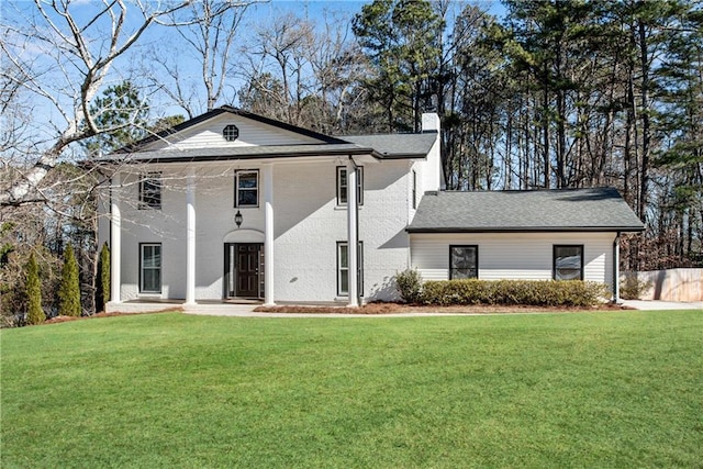 neoclassical home featuring a chimney and a front lawn