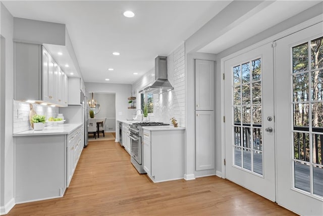 kitchen featuring french doors, light countertops, wall chimney exhaust hood, and high end stainless steel range oven