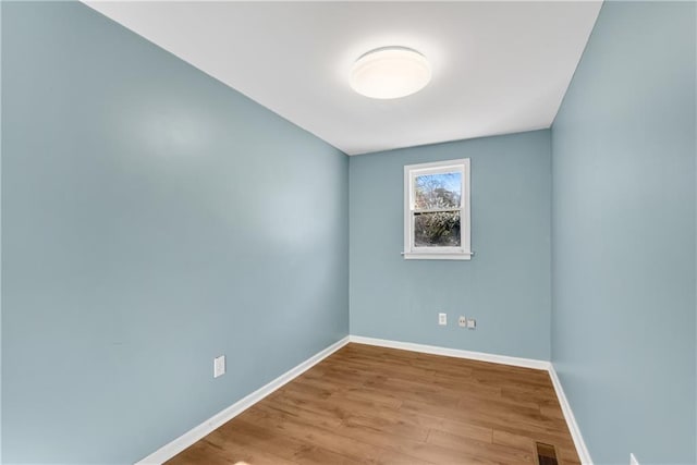 empty room featuring visible vents, wood finished floors, and baseboards