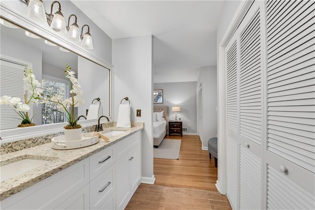 ensuite bathroom featuring a closet, wood finished floors, ensuite bathroom, and a sink