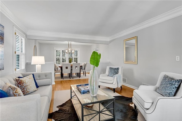 living room with crown molding, wood finished floors, baseboards, and a chandelier