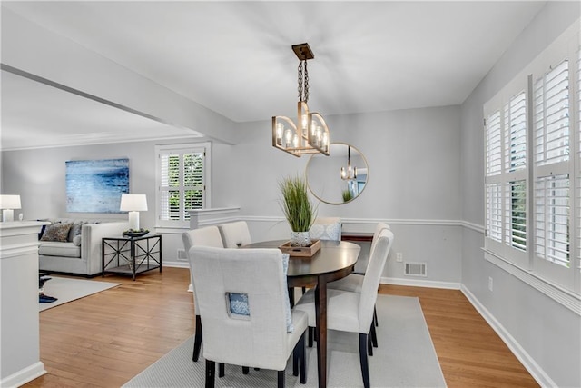 dining room with a notable chandelier, visible vents, baseboards, and wood finished floors