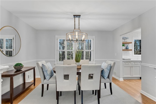 dining area featuring light wood-type flooring, baseboards, and a chandelier