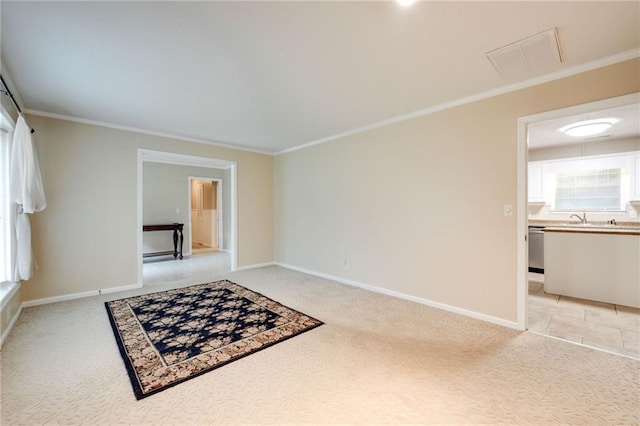 spare room featuring light colored carpet, a sink, visible vents, baseboards, and crown molding