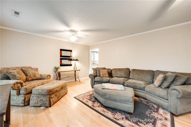 living area with a ceiling fan, visible vents, crown molding, and wood finished floors