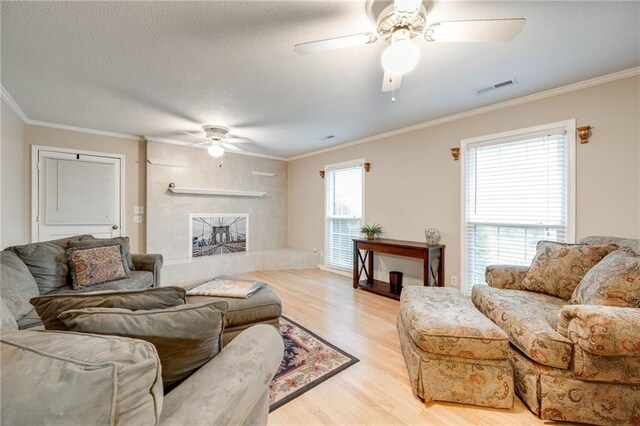 living area with visible vents, crown molding, light wood-style flooring, and a fireplace