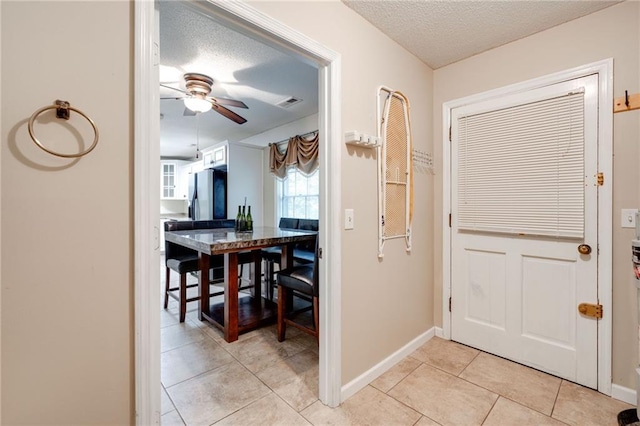 entrance foyer featuring ceiling fan, baseboards, a textured ceiling, and light tile patterned flooring