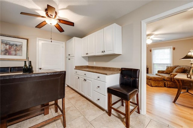 kitchen featuring light wood finished floors, dark countertops, ceiling fan, open floor plan, and white cabinetry