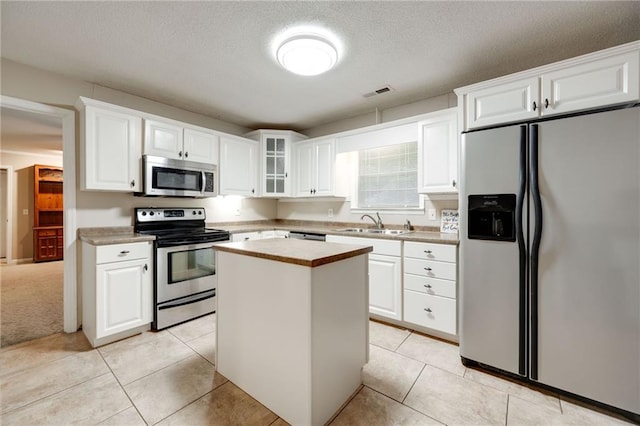 kitchen featuring stainless steel appliances, a kitchen island, glass insert cabinets, and white cabinets