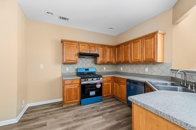 kitchen featuring dishwashing machine, visible vents, stainless steel range with gas stovetop, a sink, and under cabinet range hood