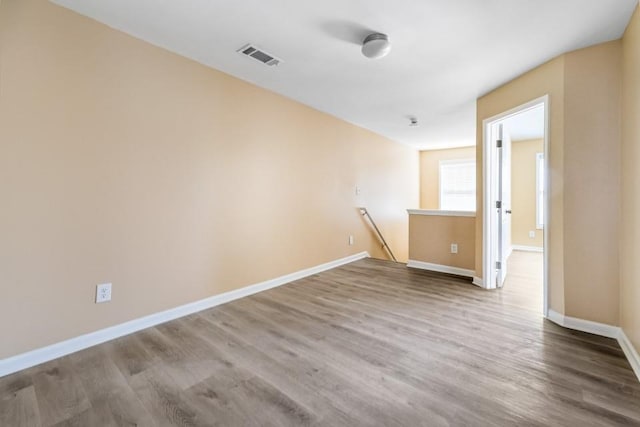 spare room featuring visible vents, baseboards, and wood finished floors