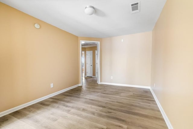 spare room featuring visible vents, baseboards, and wood finished floors