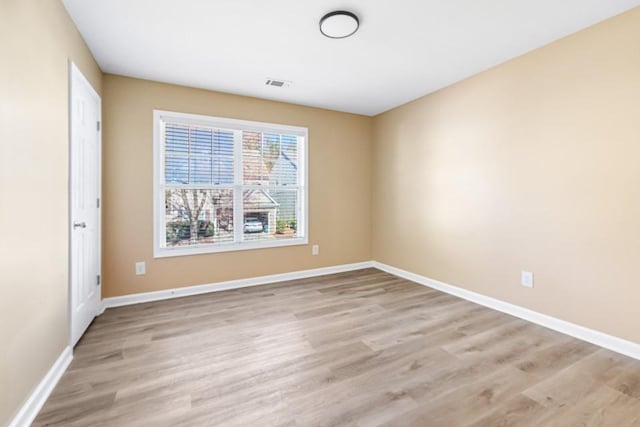 unfurnished room featuring light wood finished floors, visible vents, and baseboards