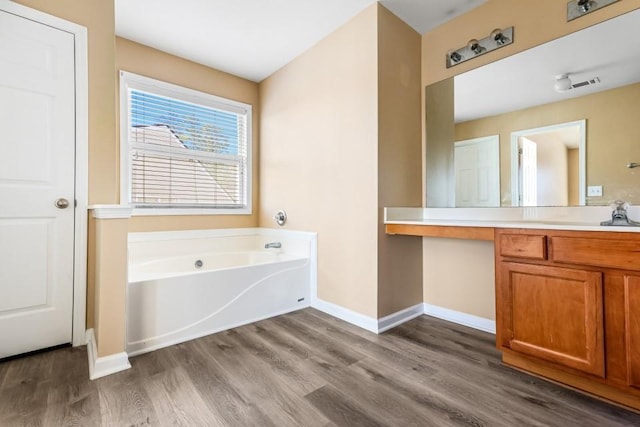 bathroom with visible vents, a garden tub, wood finished floors, baseboards, and vanity