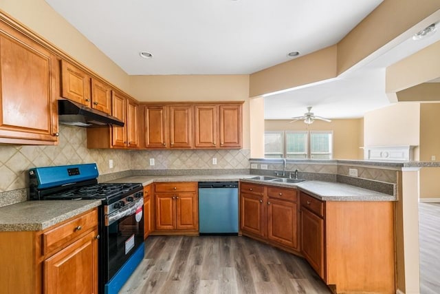 kitchen featuring stainless steel range with gas cooktop, a peninsula, under cabinet range hood, dishwasher, and brown cabinets