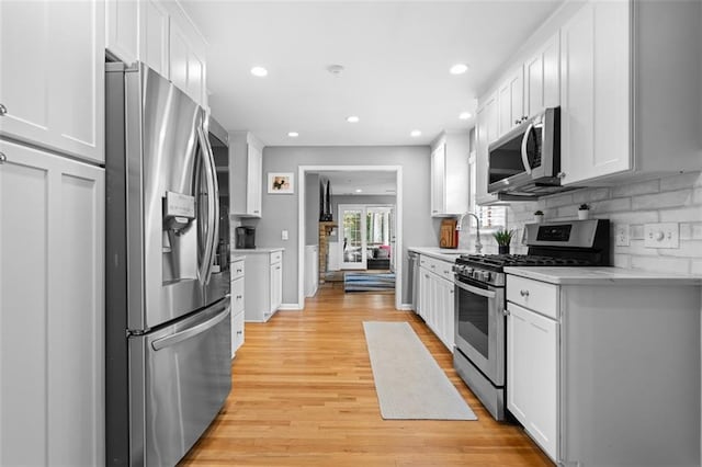 1959 Audubon Dr NE, Atlanta, GA 30329 - kitchen with stainless steel appliances, white cabinetry, light countertops, backsplash, and light wood finished floors