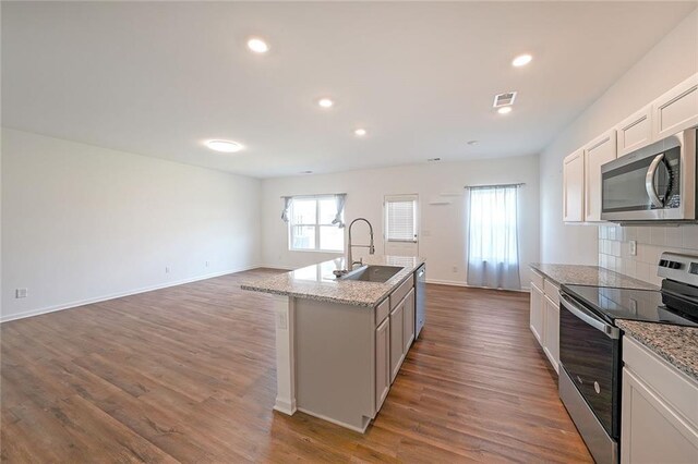 kitchen featuring stove, light stone counters, stainless steel dishwasher, sink, and light hardwood / wood-style floors