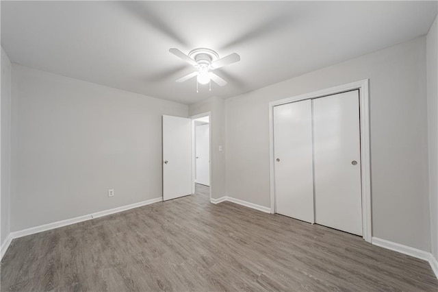unfurnished bedroom featuring a closet, ceiling fan, baseboards, and wood finished floors