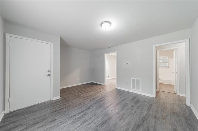 unfurnished room with wood finished floors, baseboards, and visible vents