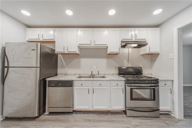 kitchen with light wood-type flooring, white cabinetry, appliances with stainless steel finishes, under cabinet range hood, and a sink