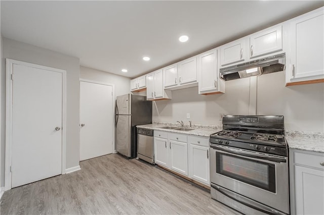 kitchen with white cabinets, under cabinet range hood, light wood-style floors, appliances with stainless steel finishes, and a sink