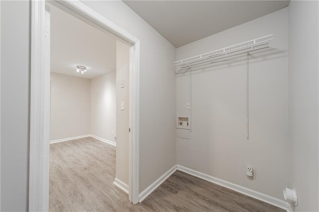 clothes washing area featuring baseboards, washer hookup, and wood finished floors