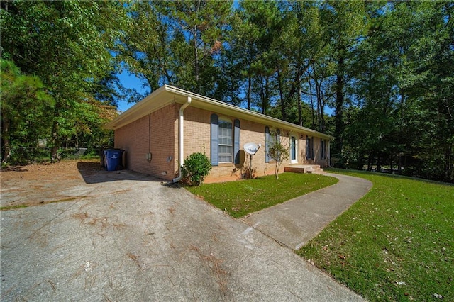 view of front facade with brick siding, driveway, and a front lawn