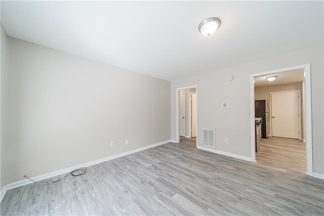 empty room with visible vents, baseboards, and light wood-style flooring