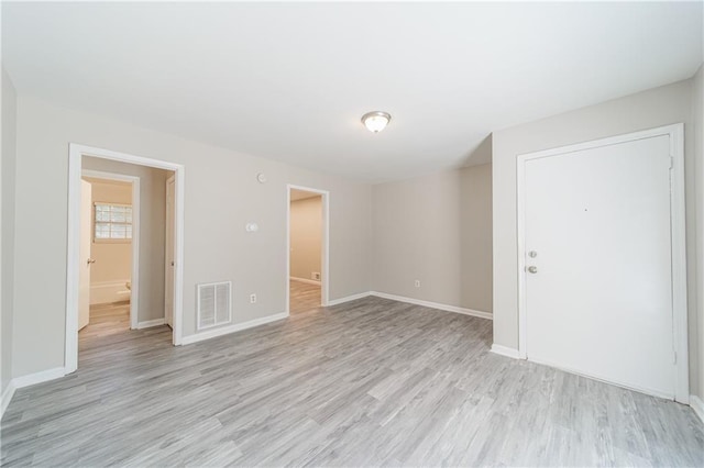 spare room with light wood finished floors, baseboards, and visible vents