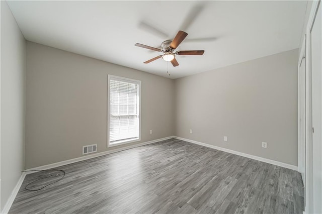 unfurnished room with visible vents, ceiling fan, baseboards, and wood finished floors