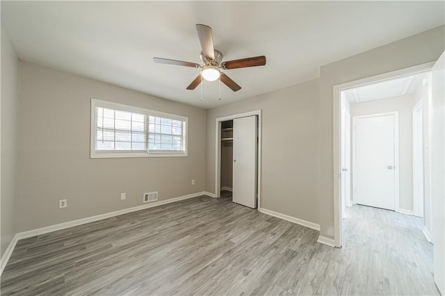unfurnished bedroom featuring a closet, baseboards, light wood-type flooring, attic access, and visible vents