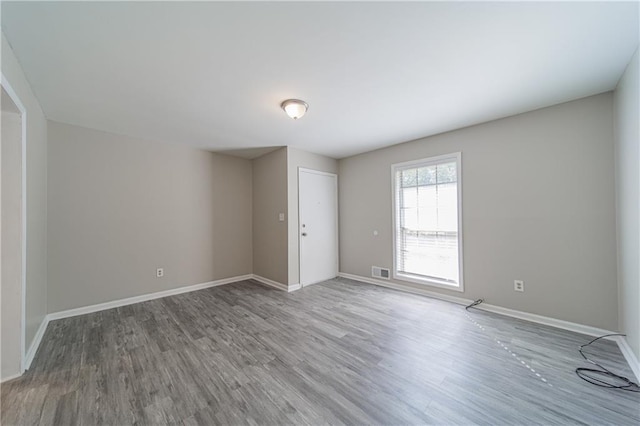 empty room with visible vents, baseboards, and wood finished floors