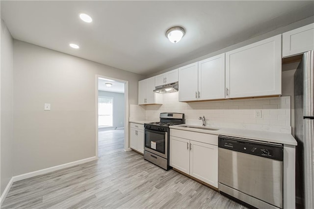 kitchen with light countertops, appliances with stainless steel finishes, a sink, and under cabinet range hood
