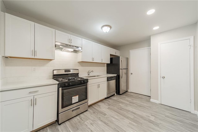kitchen featuring stainless steel appliances, under cabinet range hood, light countertops, and a sink