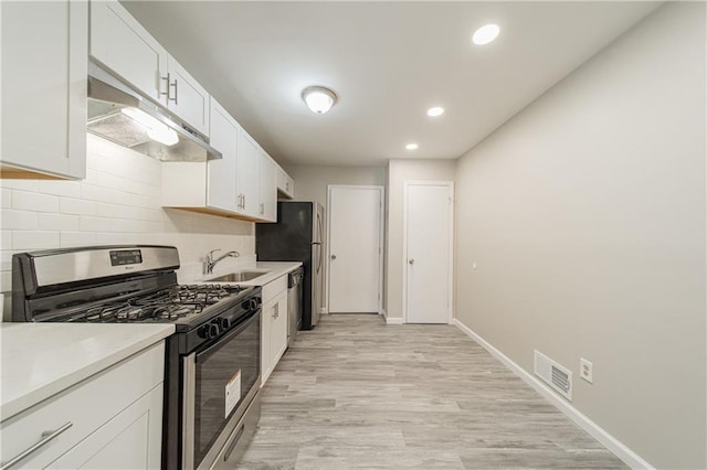 kitchen with tasteful backsplash, visible vents, under cabinet range hood, a sink, and stainless steel appliances