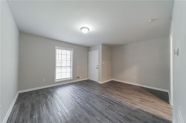 empty room with dark wood-type flooring, baseboards, and visible vents