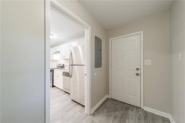 interior space featuring electric panel, light wood-style floors, baseboards, and a sink