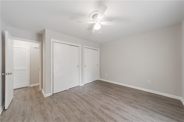 unfurnished bedroom with light wood-style floors, baseboards, two closets, and ceiling fan