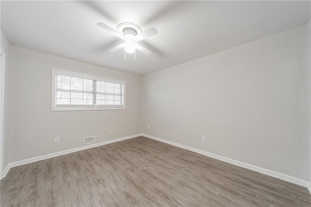 unfurnished room with wood finished floors, baseboards, a ceiling fan, and visible vents