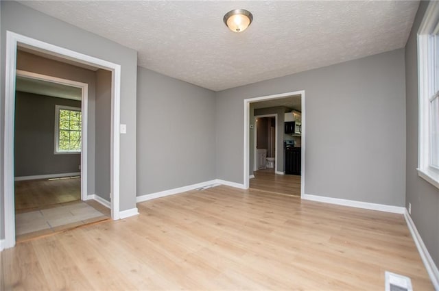 8211 Thompson St, Douglasville, GA 30134 - empty room with light wood-type flooring, baseboards, visible vents, and a textured ceiling